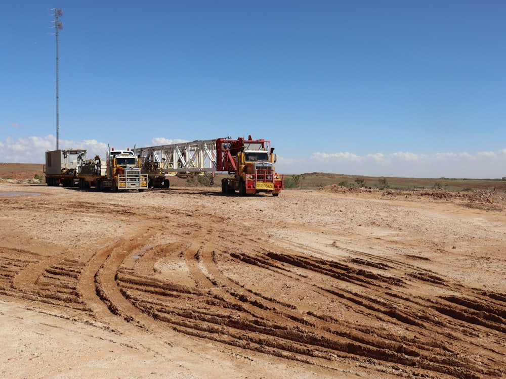 A drilling rig and trucks on a red dirt pad in the outback